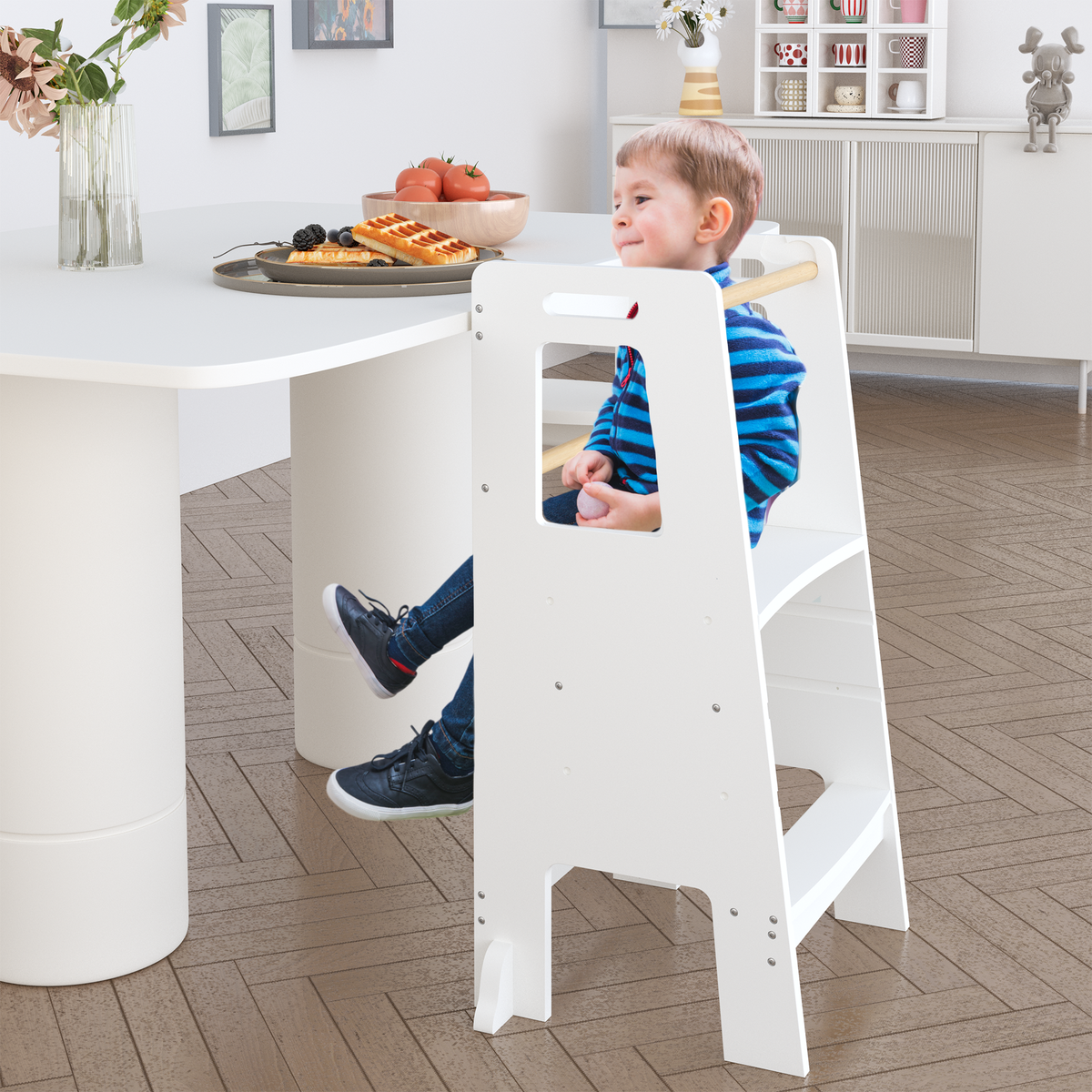 Child using the white wooden learning tower at a table